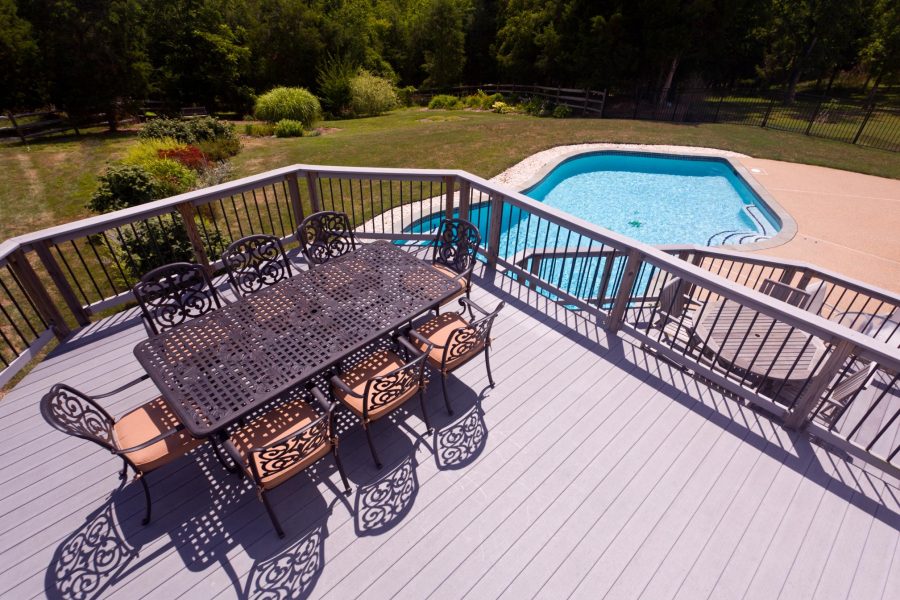 wood deck with chairs and table and a pool view